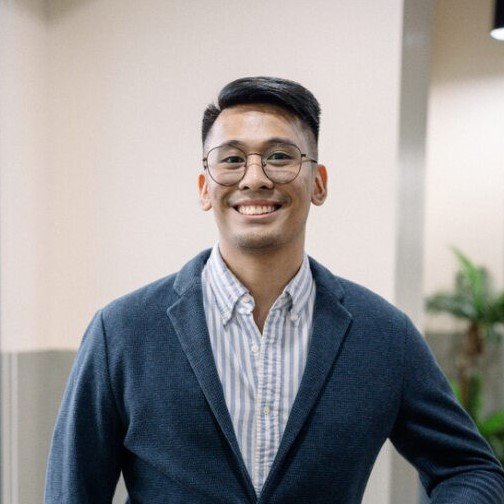 Raphael Aguilar smiling in a dark blazer and glasses